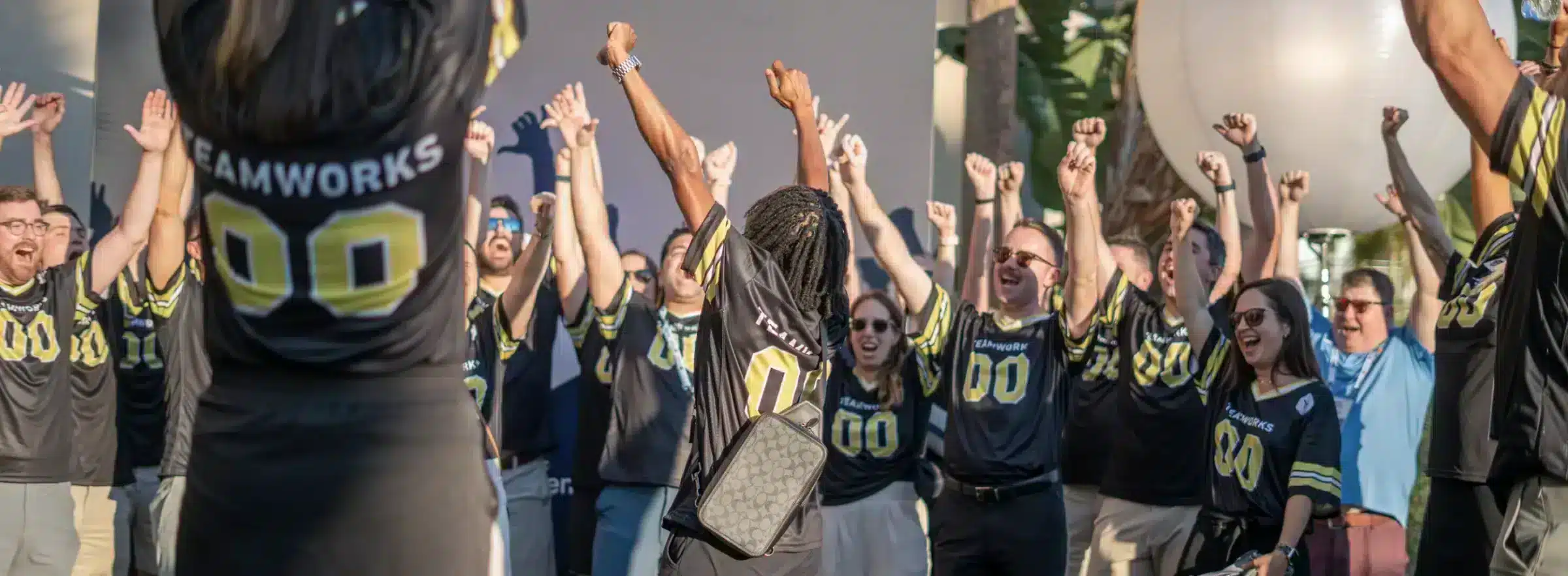 Teamworks Employees, wearing branded football jerseys, celebrating at the 2023 NACDA event.